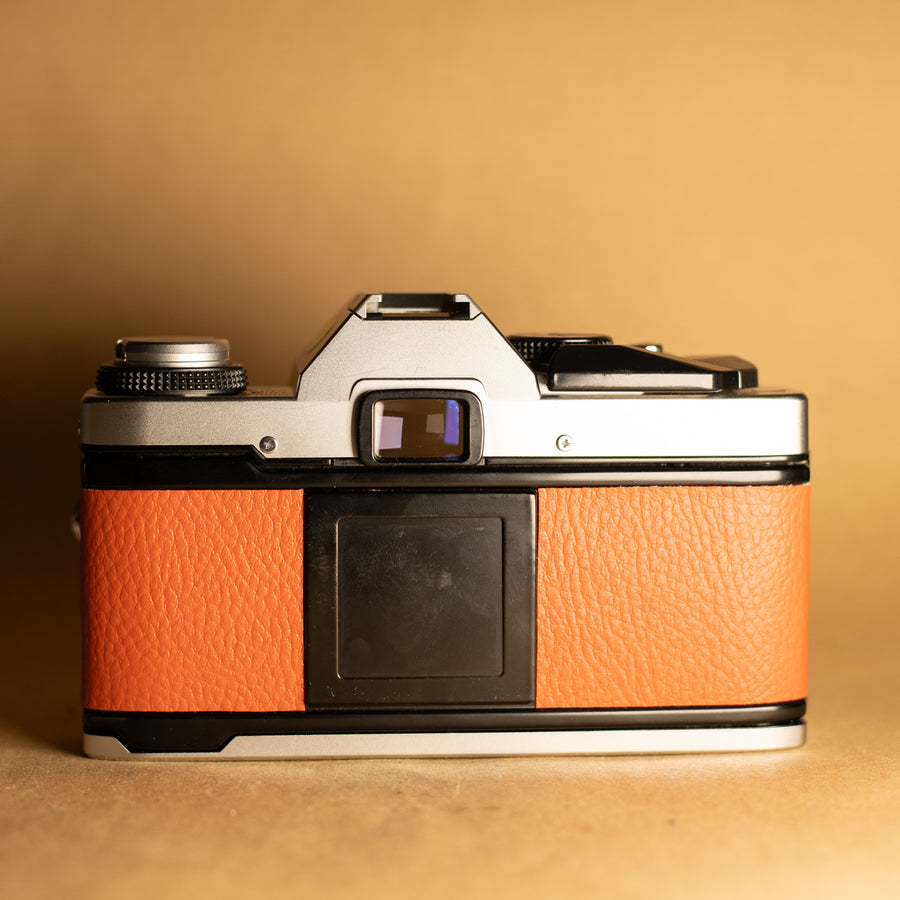 Olympus OM20 en orange avec objectif 50 mm f/1.8